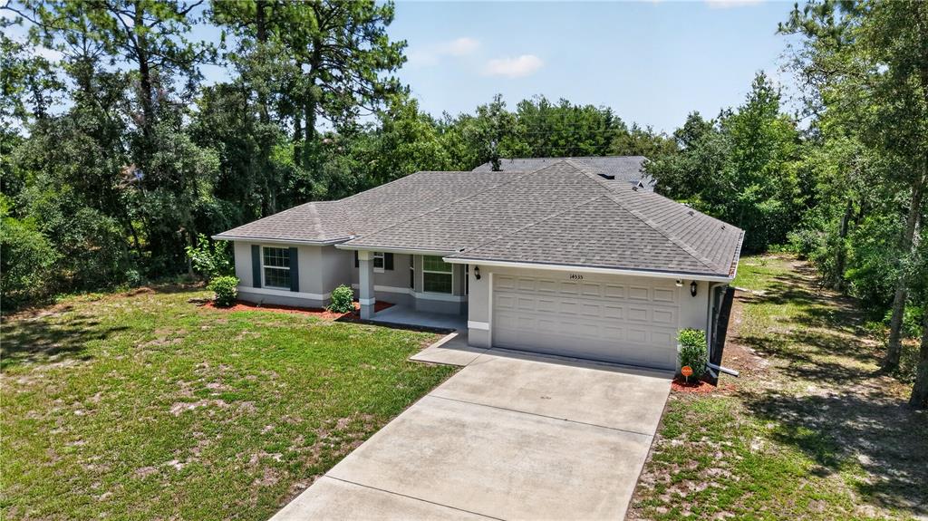 An exterior view of a single-story house with a gray roof and a concrete driveway — 14535 SW 68TH TERRACE, OCALA, FL
