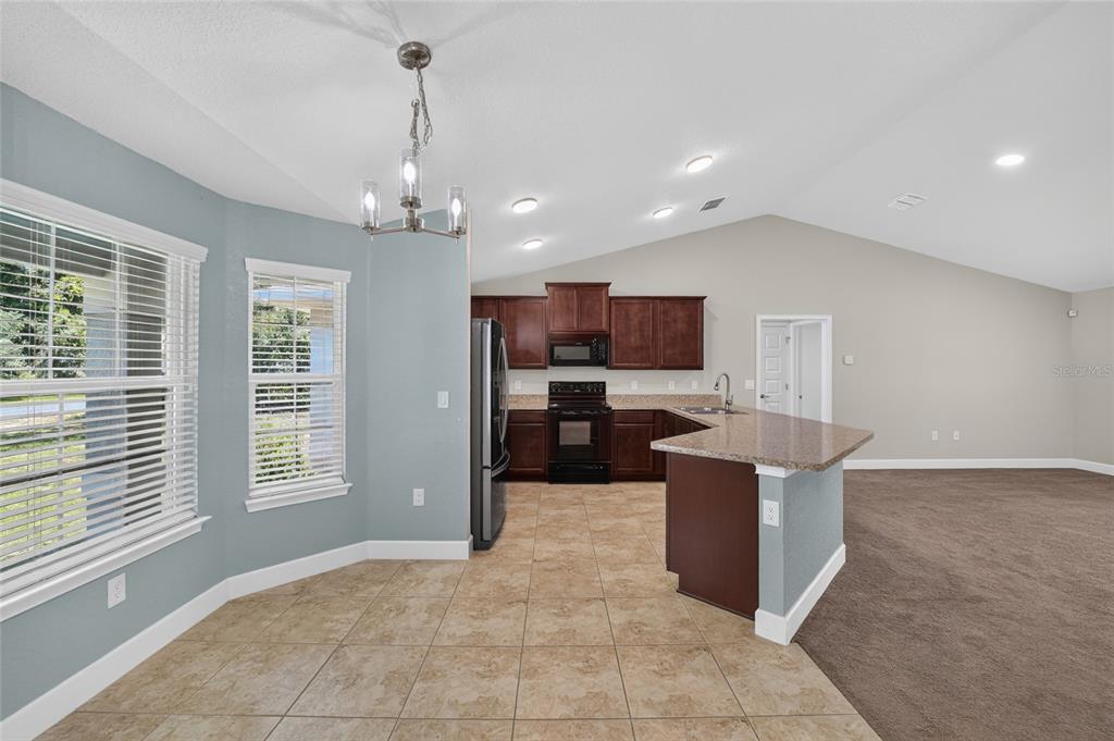 A kitchen with dark wood cabinets and a breakfast bar opens to a dining area — 14535 SW 68TH TERRACE, OCALA, FL