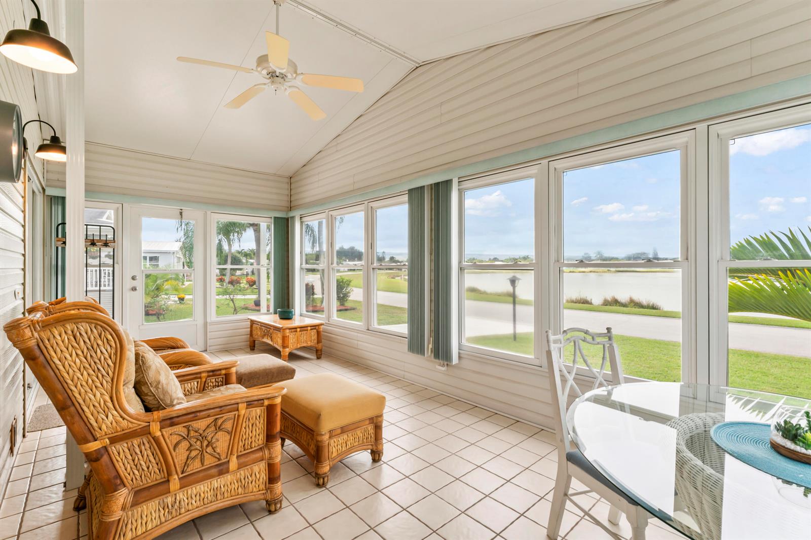 A sunroom with tiled floors, wicker furniture, a ceiling fan, and large windows overlooking water — 8913 SW Chevy Circle, Stuart FL 34997, STUART, FL