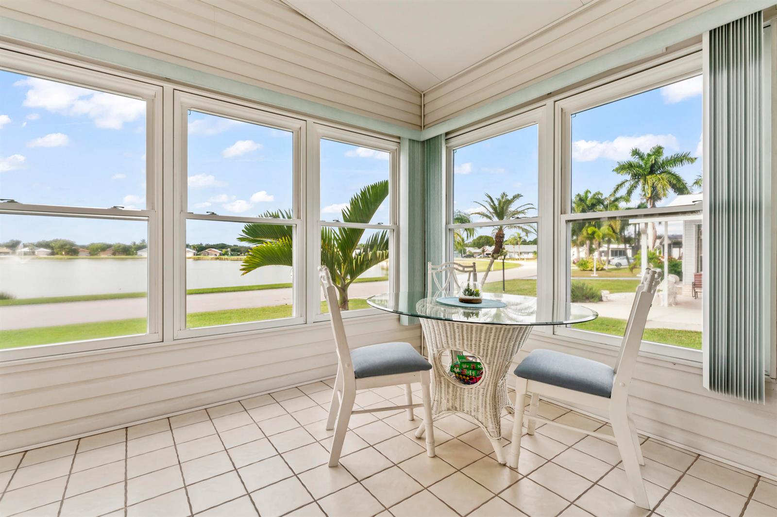 A sunroom features a glass-topped wicker table, two chairs, tiled flooring, and large windows — 8913 SW Chevy Circle, Stuart FL 34997, STUART, FL