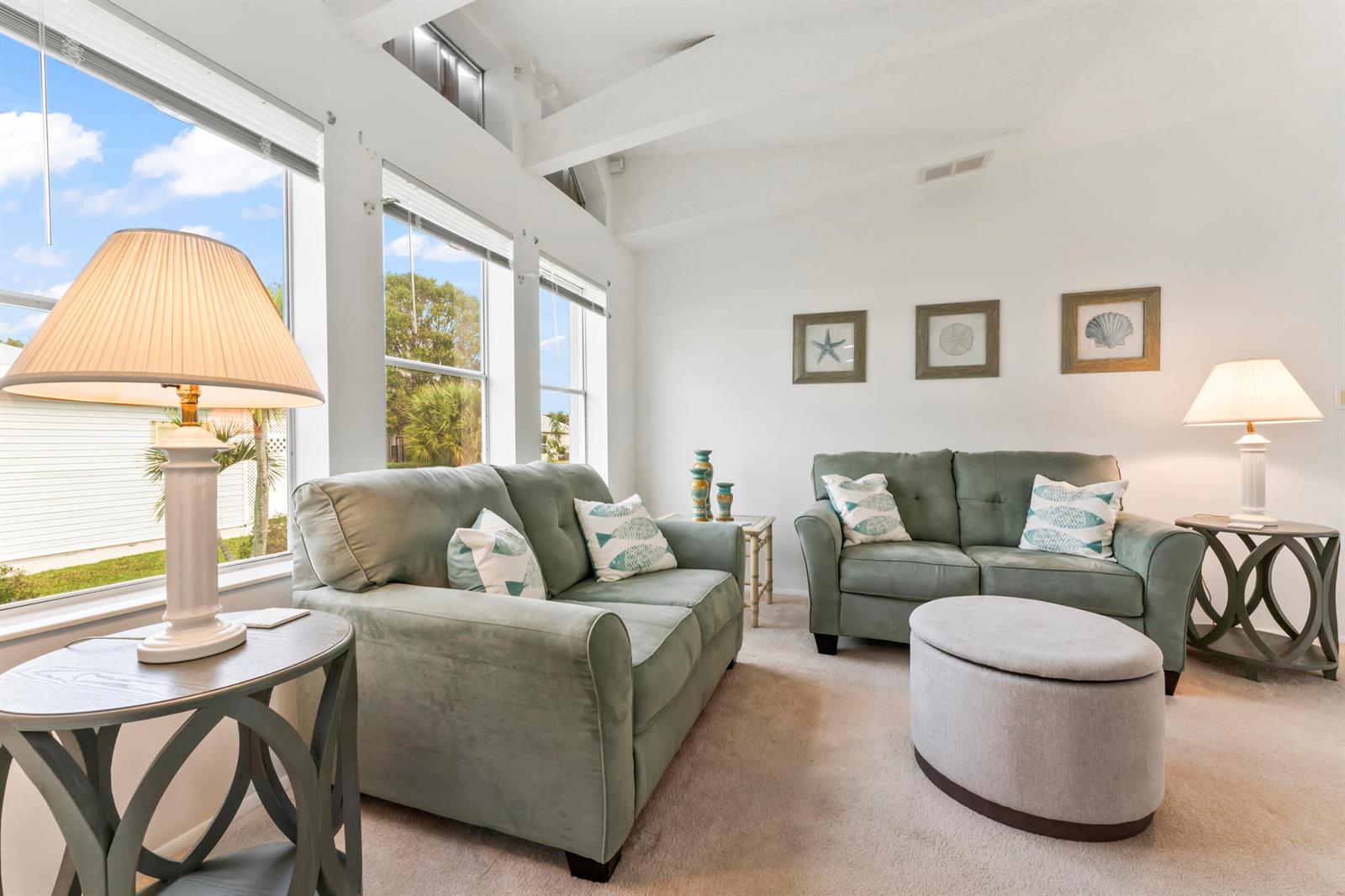 A living room features two sage green sofas, a round ottoman, and large windows — 8913 SW Chevy Circle, Stuart FL 34997, STUART, FL