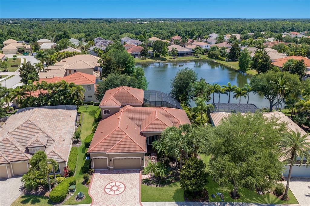 A screened-in pool and spa area with paver decking overlooking a lake at sunset — 14806 BOWFIN TERRACE, LAKEWOOD RANCH, FL