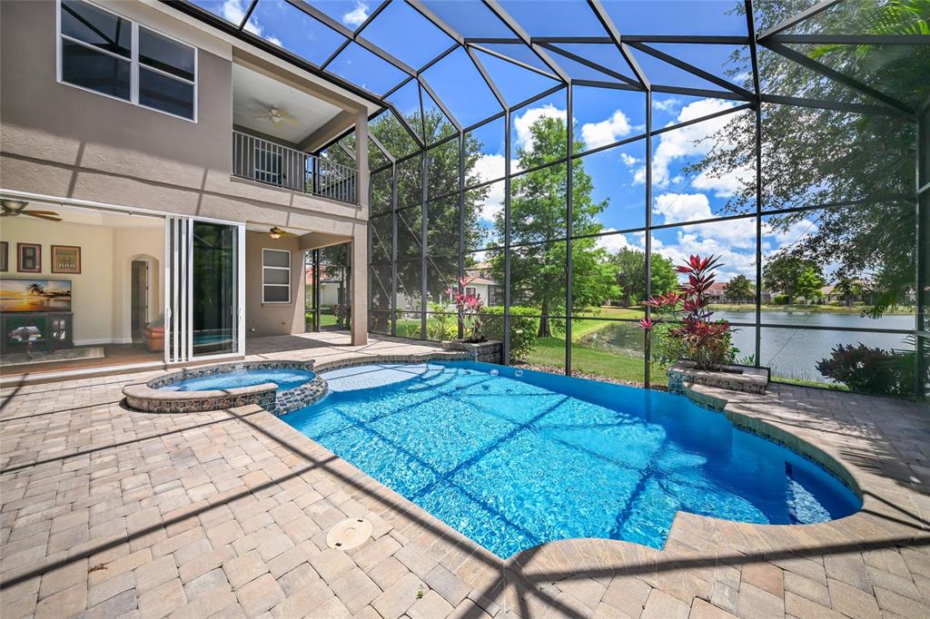 A screened-in pool and spa area with paver decking overlooking a lake and trees — 14806 BOWFIN TERRACE, LAKEWOOD RANCH, FL