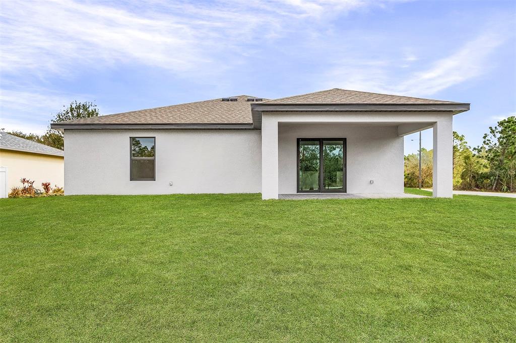 The rear exterior of a single-story house features a covered patio and a grassy yard — 2791 SNUG STREET, NORTH PORT, FL