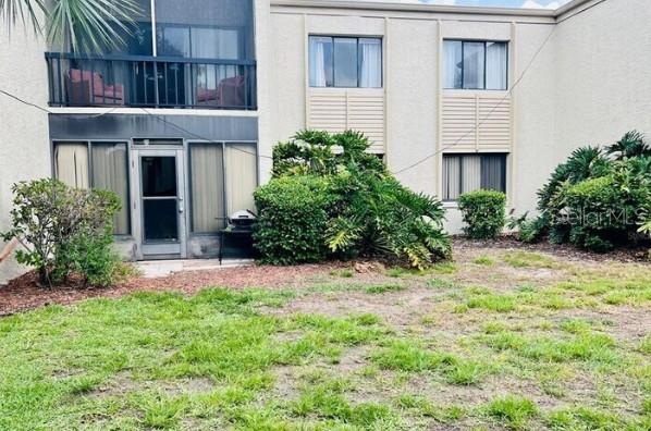 A multi-story building exterior features a ground-level patio, a second-story balcony, and surrounding landscaping — 3298 SEMORAN BOULEVARD UNIT 14, ORLANDO, FL