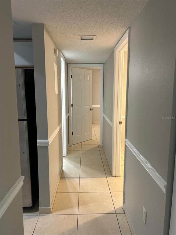 A hallway with light-colored tile flooring leads to an open white door — 3298 SEMORAN BOULEVARD UNIT 14, ORLANDO, FL