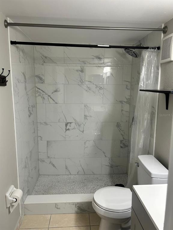 A bathroom features a walk-in shower with marble-look tile walls and a pebble floor — 3298 SEMORAN BOULEVARD UNIT 14, ORLANDO, FL