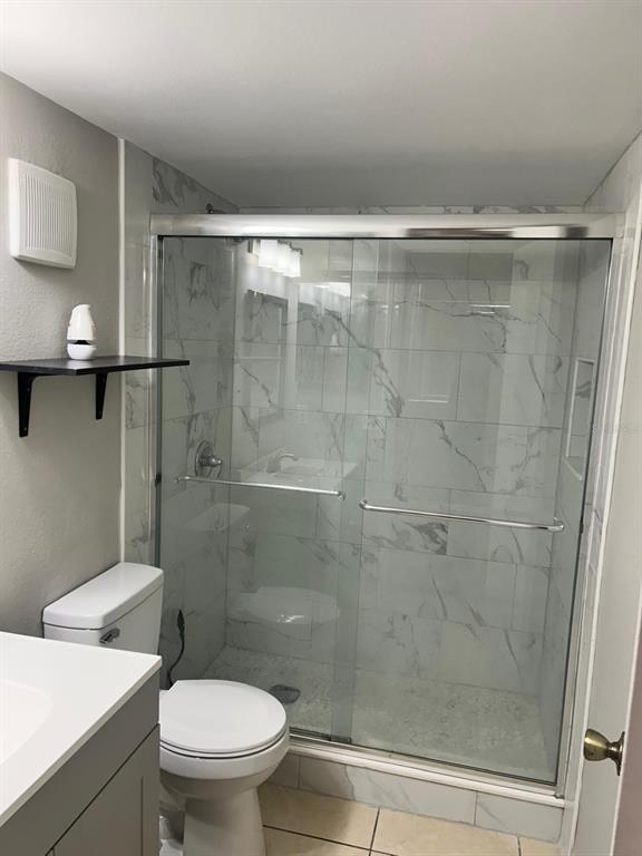 A bathroom features a walk-in shower with marble-look tile, a toilet, and a vanity — 3298 SEMORAN BOULEVARD UNIT 14, ORLANDO, FL
