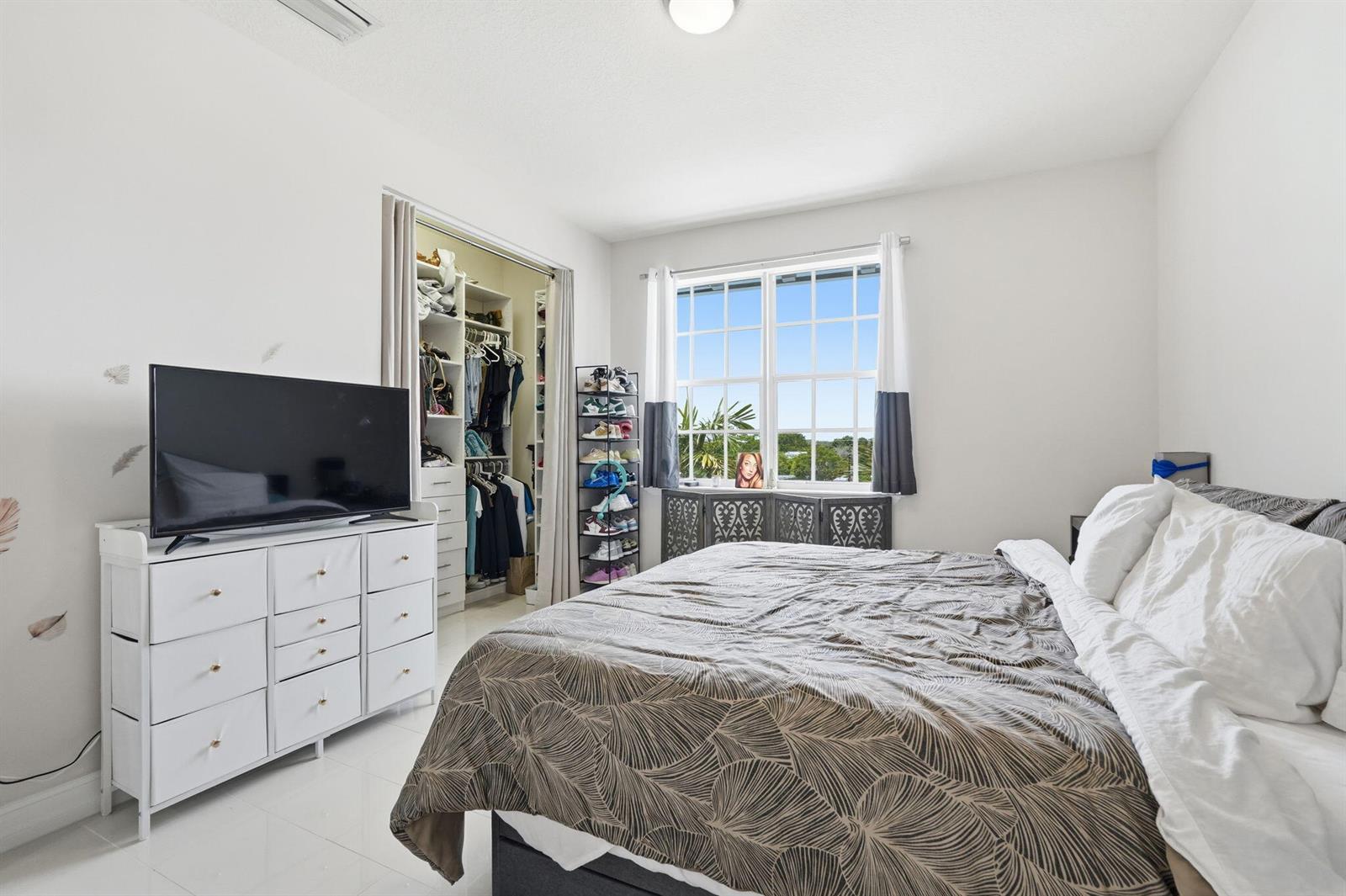 A bedroom features a white dresser, a bed with a patterned comforter, and a closet — 310 N Dixie Highway # 104, FL 33460, FL