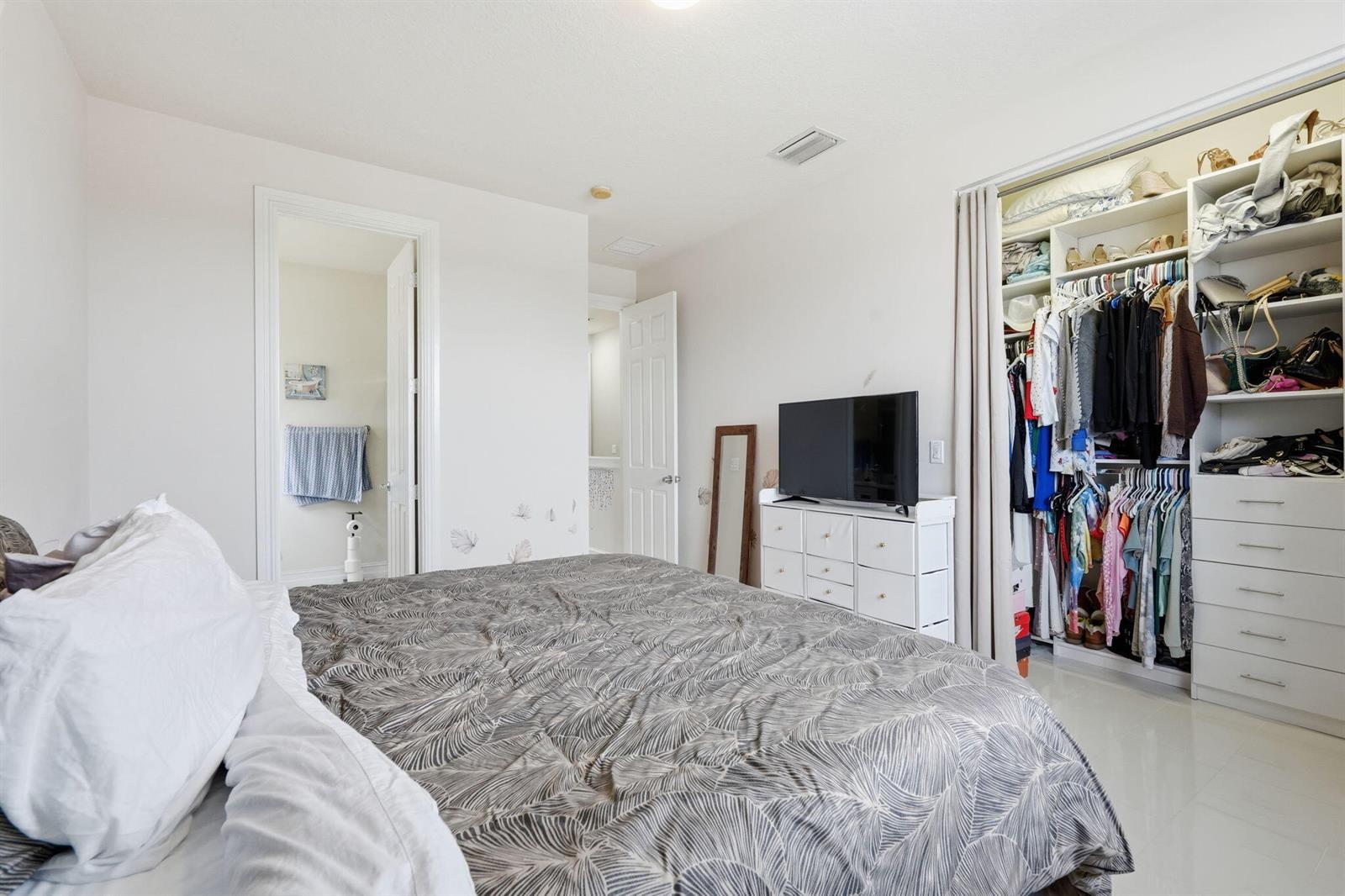 A bedroom features a bed, a dresser with a television, and an open closet — 310 N Dixie Highway # 104, FL 33460, FL