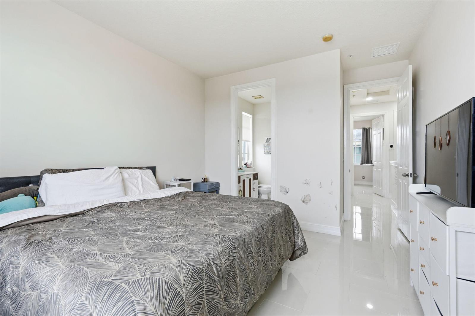 A bedroom with a bed, white dresser, tiled floors, and an attached bathroom — 310 N Dixie Highway # 104, FL 33460, FL