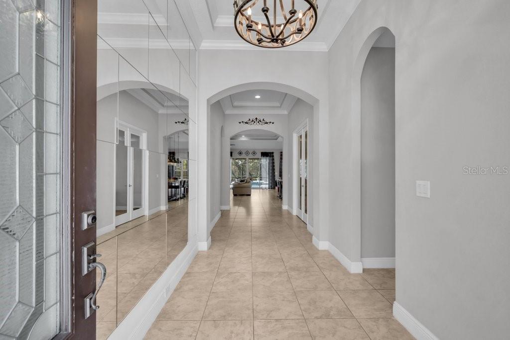 A bright foyer features light tile flooring, a mirrored wall, and an arched entryway — 15409 STARLING CROSSING DRIVE, LITHIA, FL