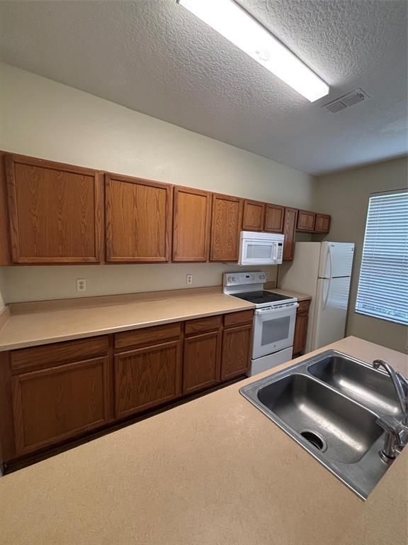 A kitchen features wood cabinets, tan countertops, white appliances, and a double-basin sink — 2417 TEMPLE GROVE LANE, KISSIMMEE, FL