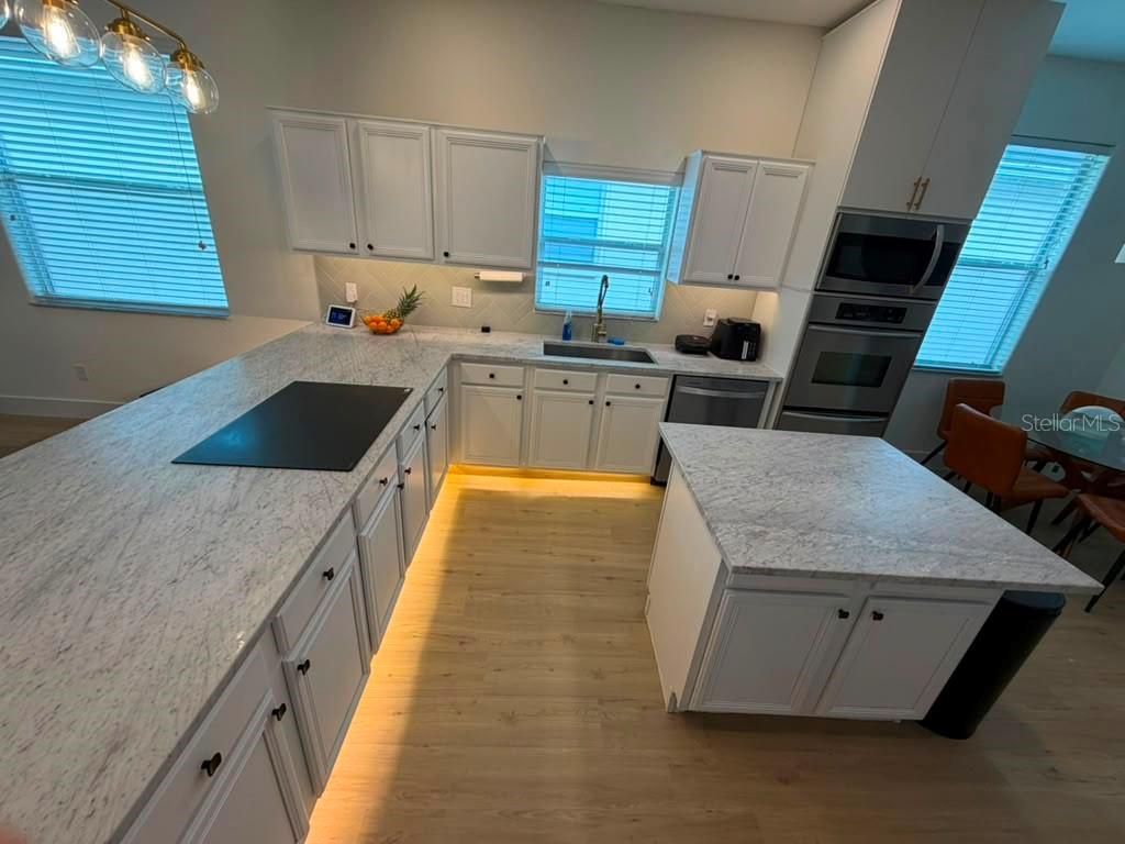 A kitchen features white cabinets, granite countertops, a center island, and under-cabinet lighting — 14539 SAINT GEORGES HILL DRIVE, ORLANDO, FL