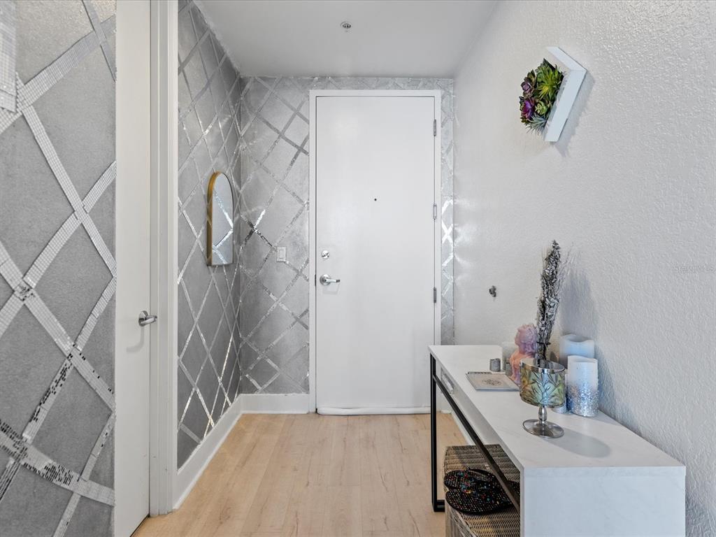 An entryway features light wood flooring, a white console table, and a silver geometric accent wall — 150 E ROBINSON STREET UNIT 2906, ORLANDO, FL