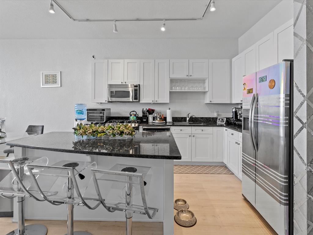 A kitchen features white cabinets, dark granite countertops, a central island, and stainless steel appliances — 150 E ROBINSON STREET UNIT 2906, ORLANDO, FL