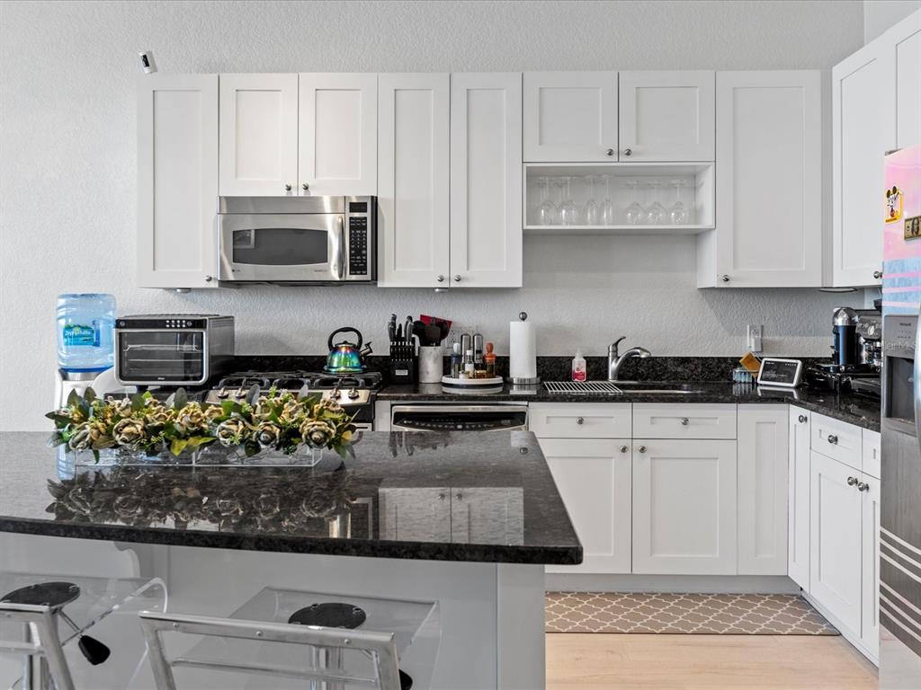 A kitchen features white cabinets, dark granite countertops, a center island, and stainless steel appliances — 150 E ROBINSON STREET UNIT 2906, ORLANDO, FL
