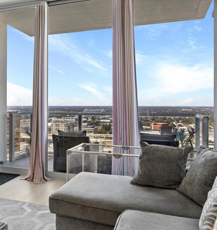 A living room with a gray sectional sofa overlooks a city view from a balcony — 150 E ROBINSON STREET UNIT 2906, ORLANDO, FL