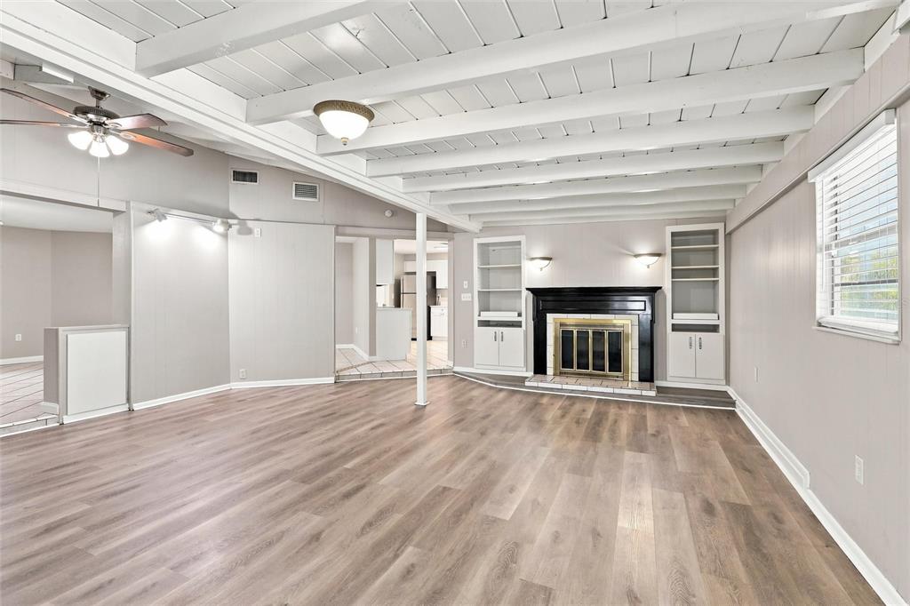 A living room features wood-look flooring, a white beamed ceiling, and a black fireplace — 131 DEGAS DRIVE, NOKOMIS, FL