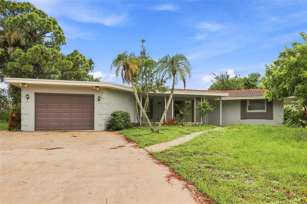 A single-story house with a brown garage door, palm trees, and a concrete driveway — 131 DEGAS DRIVE, NOKOMIS, FL
