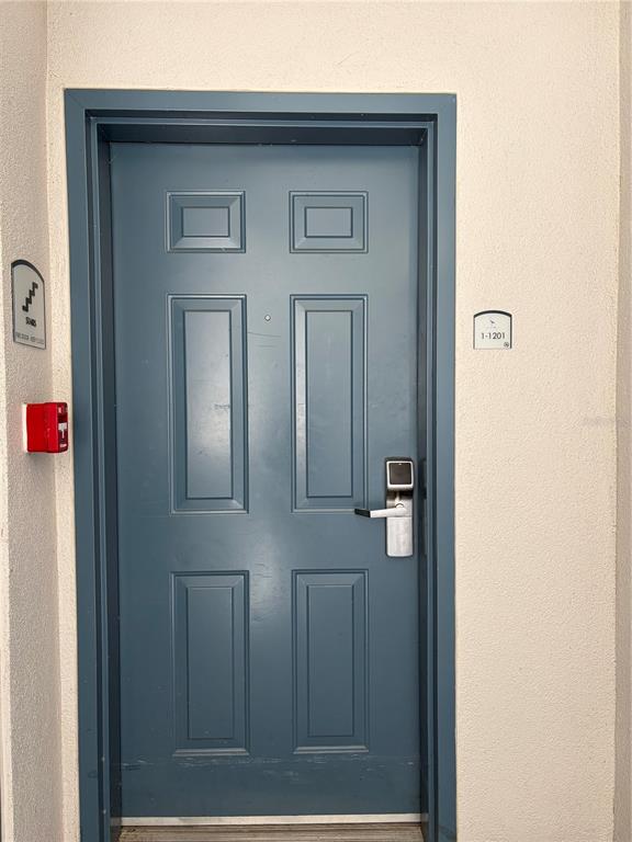 A blue six-panel door with a digital lock is set in a beige wall — 13415 BLUE HERON BEACH DRIVE UNIT 1201, ORLANDO, FL