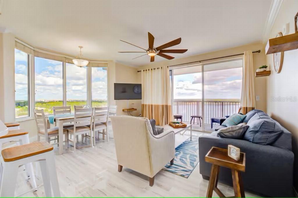 A bright living and dining area features large windows, a ceiling fan, and balcony access — 13415 BLUE HERON BEACH DRIVE UNIT 1201, ORLANDO, FL