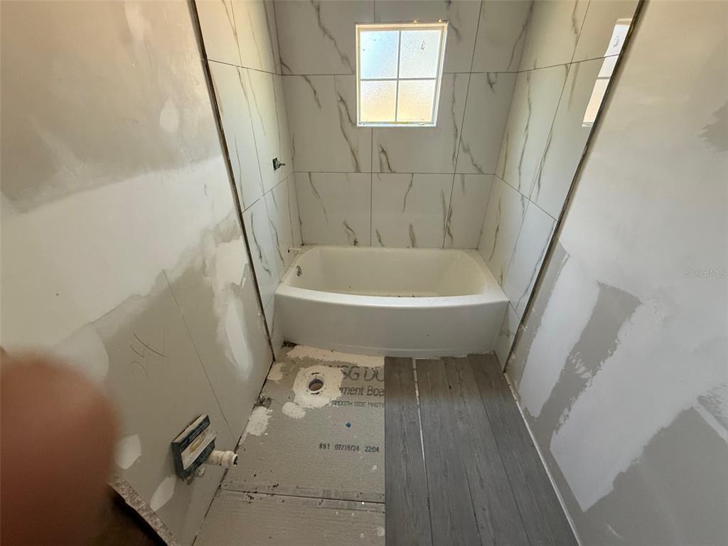 A bathroom under renovation features a bathtub with tiled walls and unfinished drywall — 2432 CHASE AVENUE, SANFORD, FL
