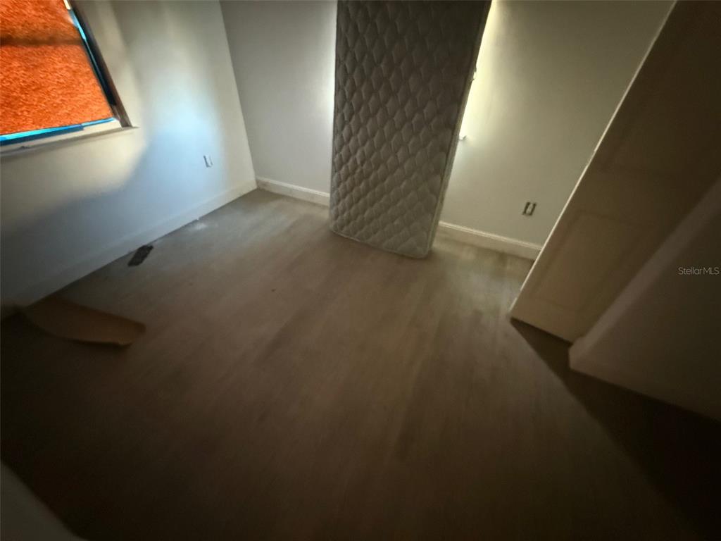 An empty bedroom features light wood flooring, white walls, and a mattress leaning against a wall — 2432 CHASE AVENUE, SANFORD, FL