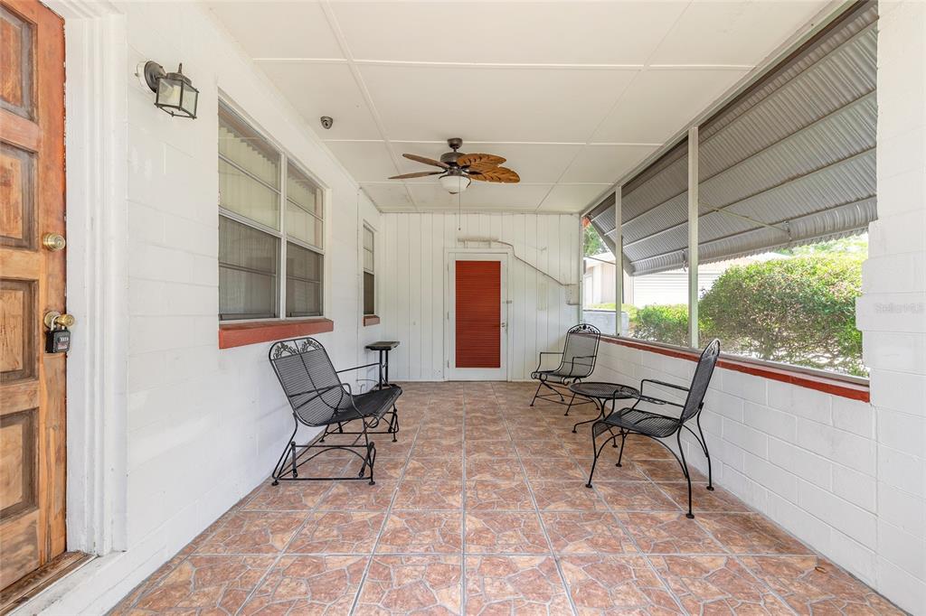 A covered patio features tiled flooring, a ceiling fan, and black metal outdoor furniture — 1584 VALENCIA AVENUE, DAYTONA BEACH, FL