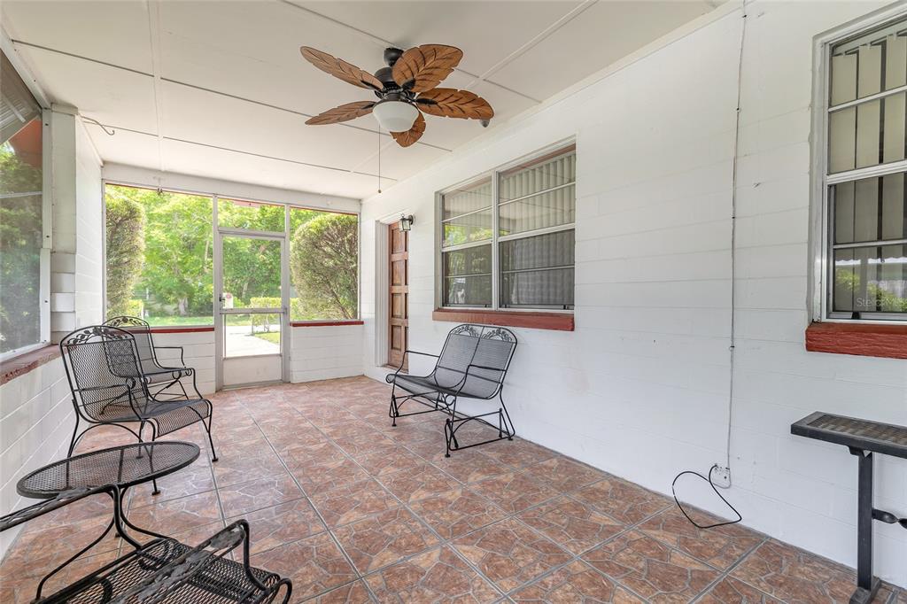 A covered porch features tiled flooring, a ceiling fan, and several pieces of metal furniture — 1584 VALENCIA AVENUE, DAYTONA BEACH, FL