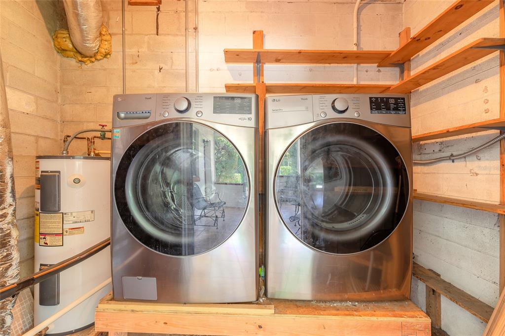 A laundry room features a washer and dryer set on a wooden platform beside a water heater — 1584 VALENCIA AVENUE, DAYTONA BEACH, FL