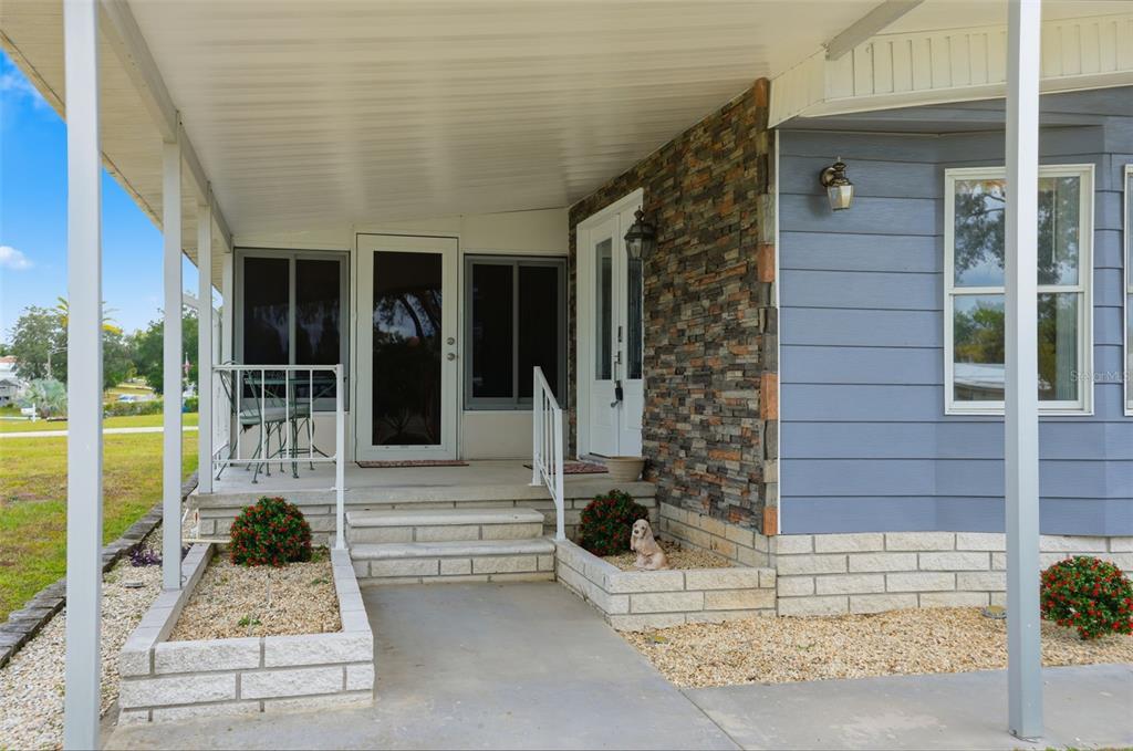 A covered porch features stone veneer siding, concrete steps, and a white metal railing — 8156 BAYCREST DRIVE, BROOKSVILLE, FL