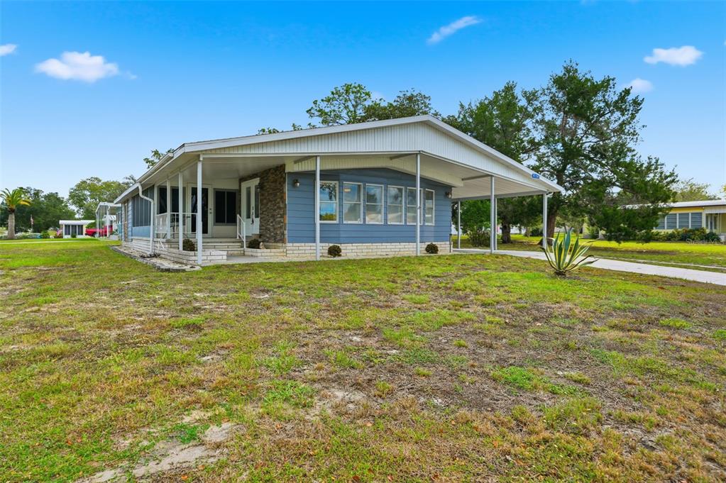 A blue mobile home with a stone accent wall, a carport, and a screened-in porch — 8156 BAYCREST DRIVE, BROOKSVILLE, FL