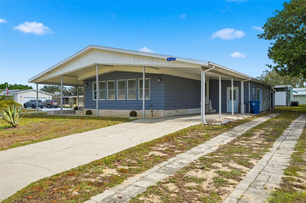 A blue manufactured home with a large carport and a concrete driveway — 8156 BAYCREST DRIVE, BROOKSVILLE, FL