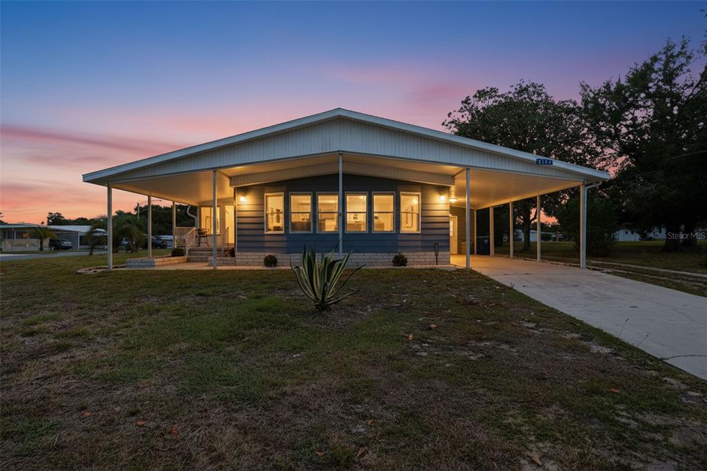 A single-story house with a large carport and a front-facing bay of windows at sunset — 8156 BAYCREST DRIVE, BROOKSVILLE, FL