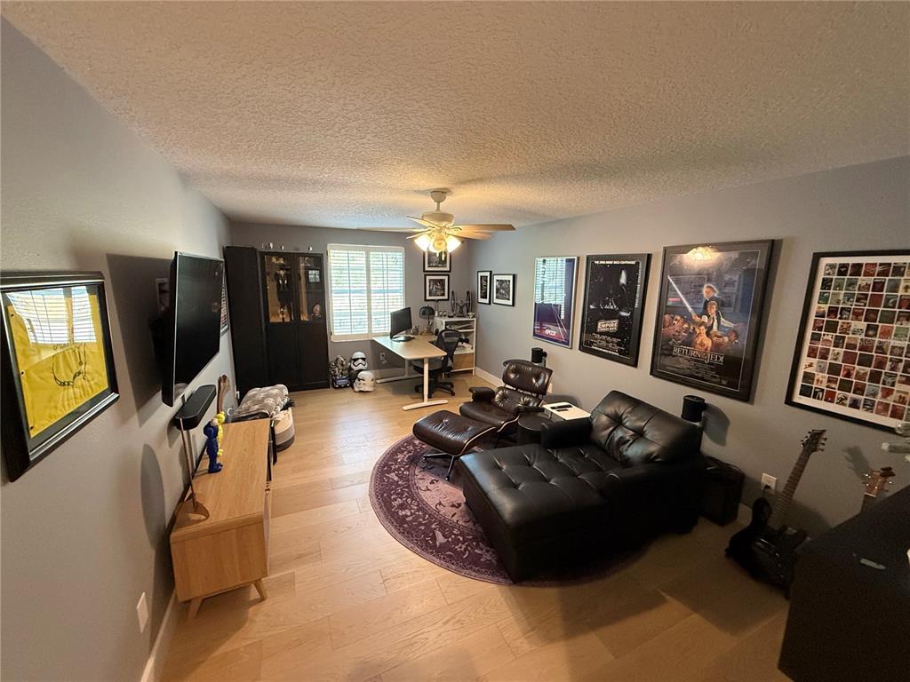 A room with light wood floors, a black leather sofa, and Star Wars wall art — 3425 TURNINGWIND LANE, WINTER GARDEN, FL