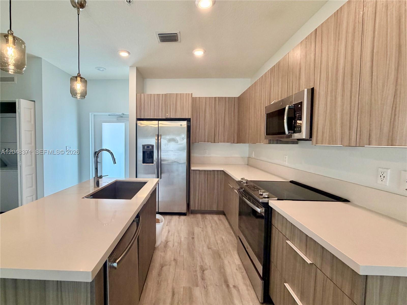 A modern kitchen features light wood cabinets, stainless steel appliances, and a white quartz island — 4740 NW 84th Ct # 33, Doral FL 33166, DORAL, FL