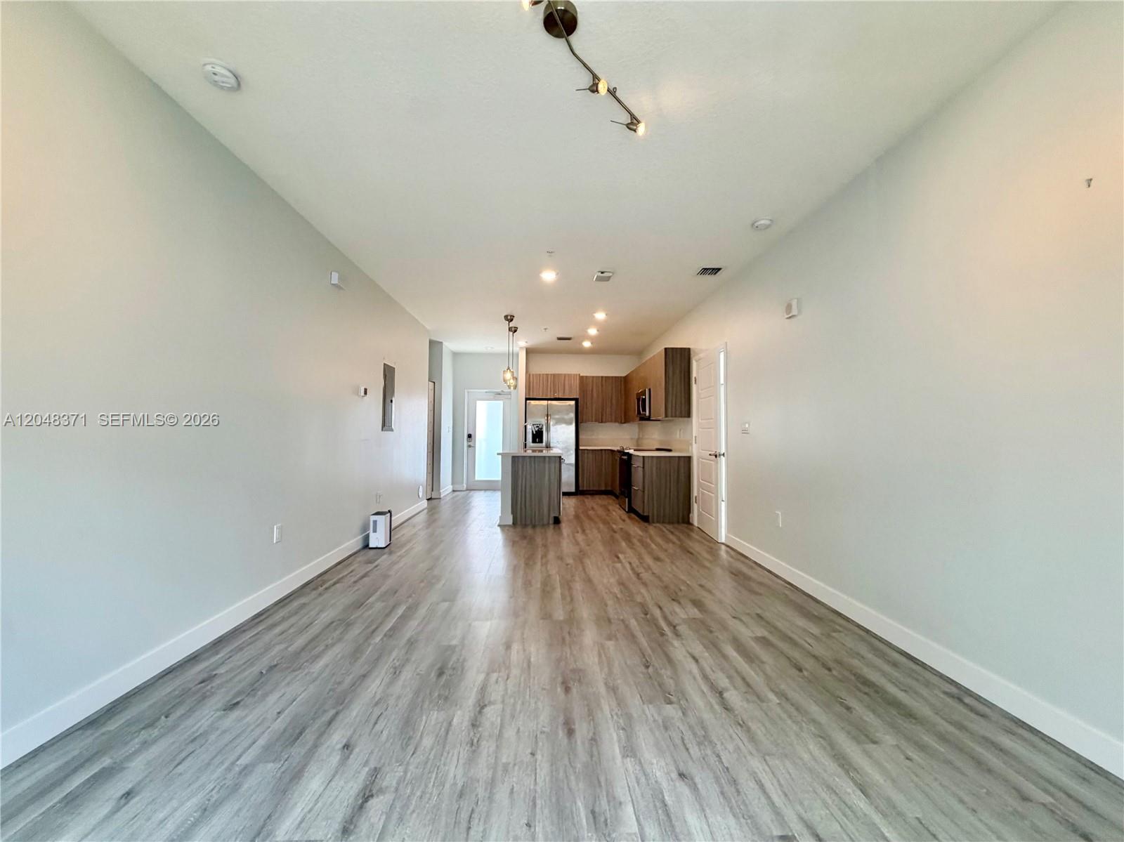 An open-concept living area features light wood-look flooring and a kitchen with dark cabinetry — 4740 NW 84th Ct # 33, Doral FL 33166, DORAL, FL
