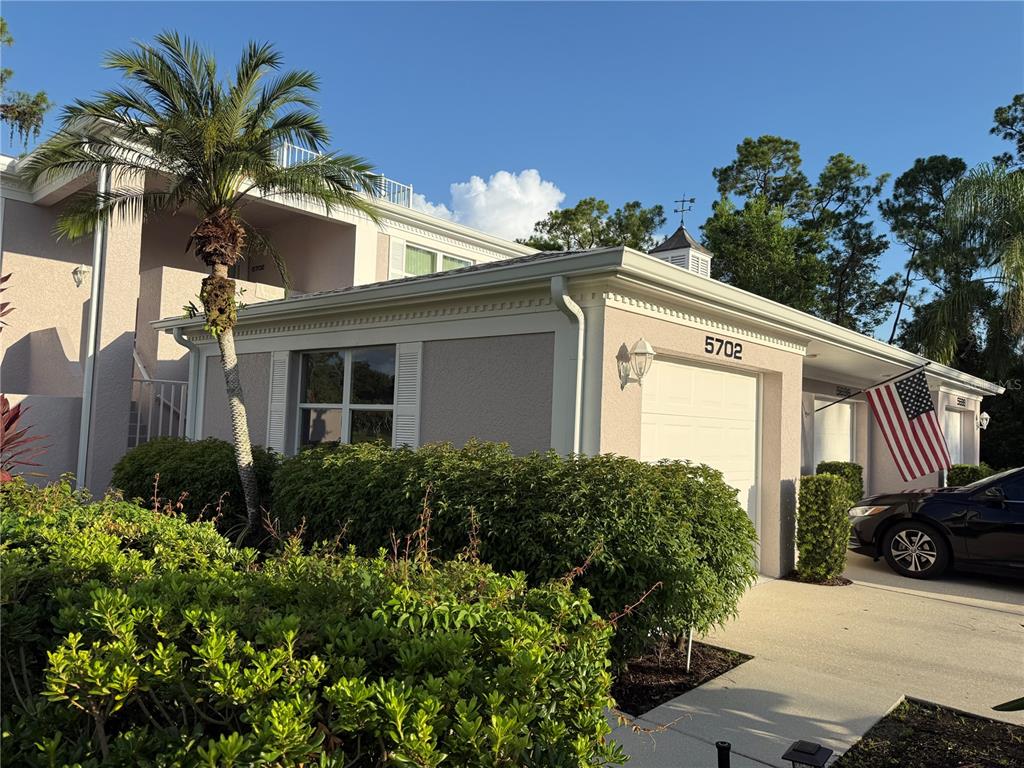 A two-story residential building features a garage, a palm tree, and a displayed American flag — 5700 SHEFFIELD GREENE CIRCLE UNIT 87, SARASOTA, FL