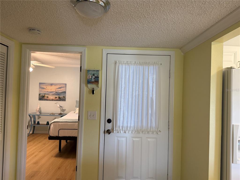 A white door with a curtain stands next to a doorway leading into a bedroom — 5700 SHEFFIELD GREENE CIRCLE UNIT 87, SARASOTA, FL