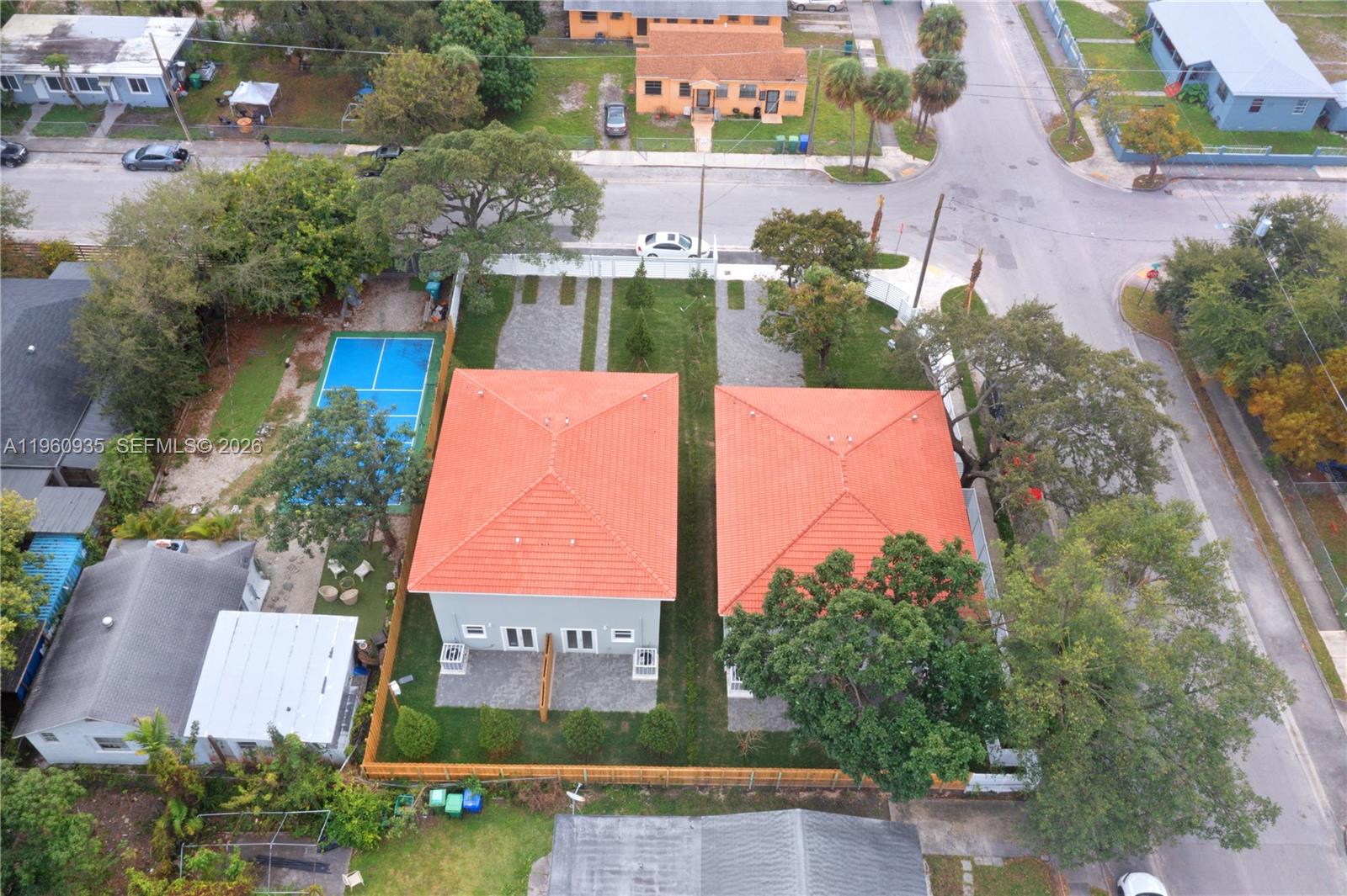 An aerial view shows two houses with orange tile roofs, a blue sports court, and landscaping — 529 NW 56th St, Miami FL 33127, MIAMI, FL