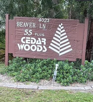 A wooden sign for a 55-plus community stands in a landscaped garden area — 4022 BEAVER LANE UNIT 800A, PORT CHARLOTTE, FL