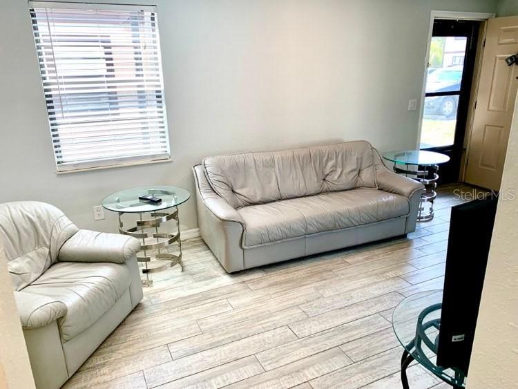 A living room features light-colored leather furniture, tile flooring, and a window with blinds — 4022 BEAVER LANE UNIT 800A, PORT CHARLOTTE, FL