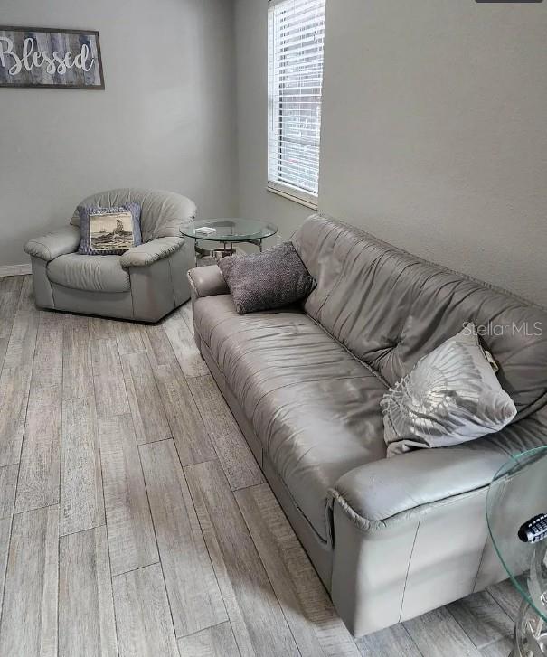 A living room features a gray leather sofa, a matching armchair, and wood-look flooring — 4022 BEAVER LANE UNIT 800A, PORT CHARLOTTE, FL
