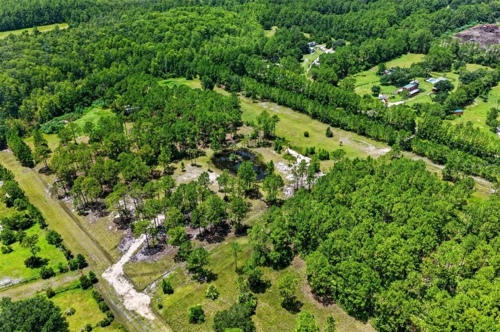 An aerial view shows a large, wooded lot featuring a small pond and grassy clearings — 0 TWIN LAKES ROAD, BUNNELL, FL