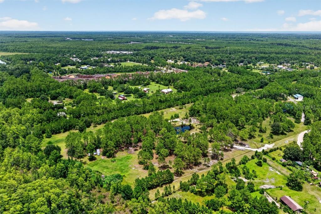 An aerial view shows a rural property with wooded areas, open fields, and a small pond — 0 TWIN LAKES ROAD, BUNNELL, FL
