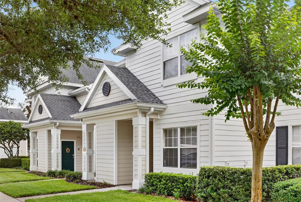 The exterior of a two-story white house with a covered entryway and green front door — 1300 EASTERN PECAN PLACE UNIT 102, WINTER GARDEN, FL