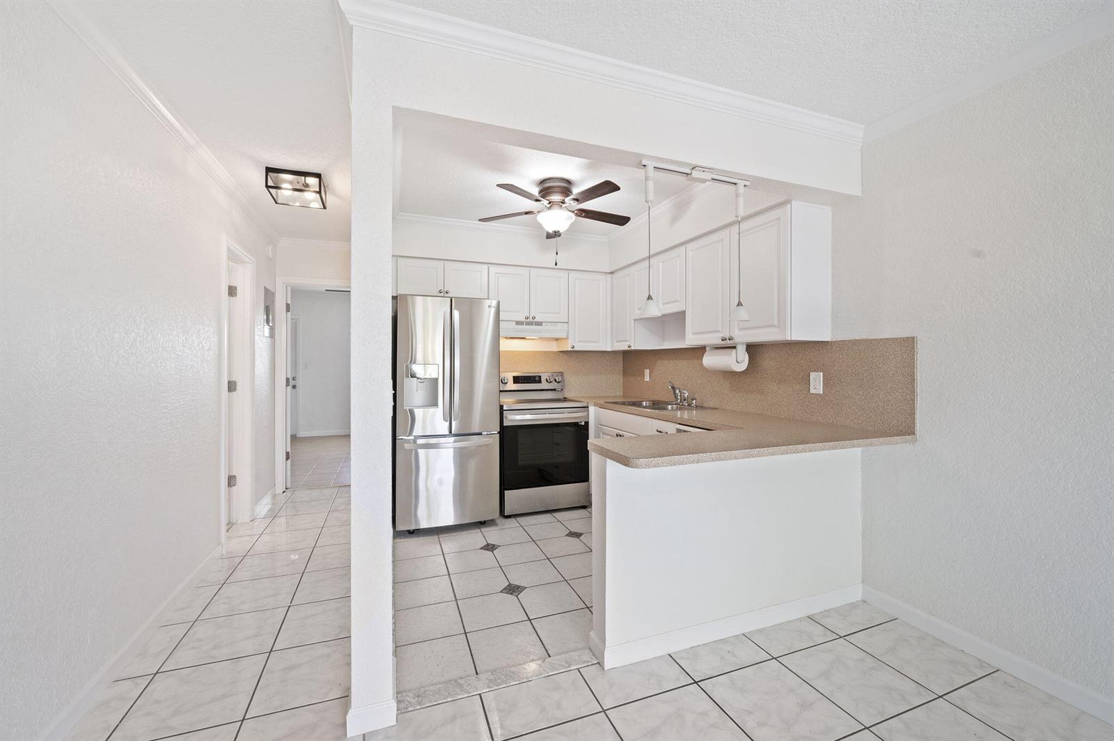 A room with white tile floors, a wood-paneled accent wall, and a mounted television — 1780 SE 4th Street, Pompano Beach FL 33060, POMPANO BEACH, FL