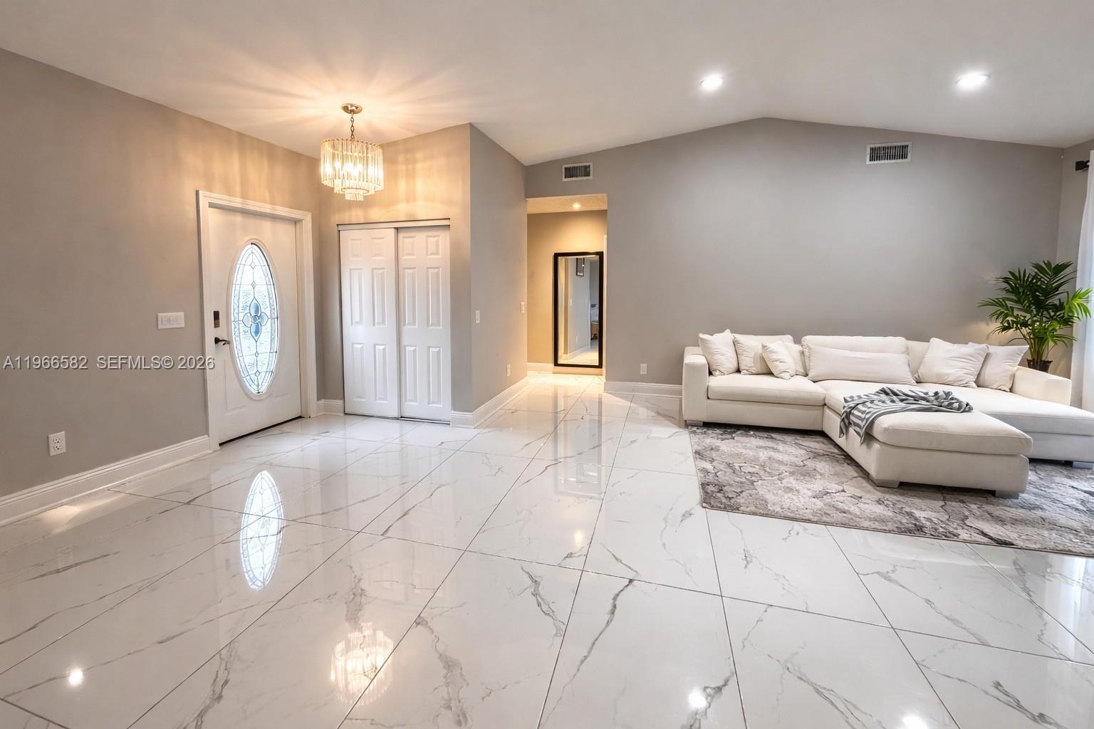 A living room features white marble-look tile flooring, a white sectional sofa, and a chandelier — 20888 Sugarloaf Ln, Boca Raton FL 33428, BOCA RATON, FL