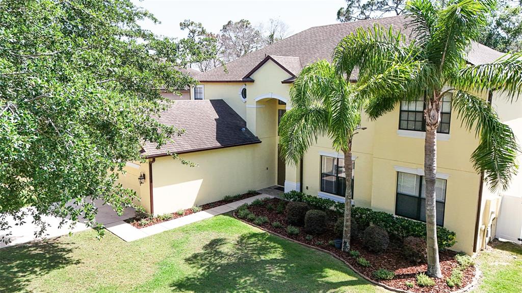 A two-story yellow stucco house with a brown shingled roof and a palm tree — 1778 WATERSIDE OAKS DRIVE, ORANGE CITY, FL